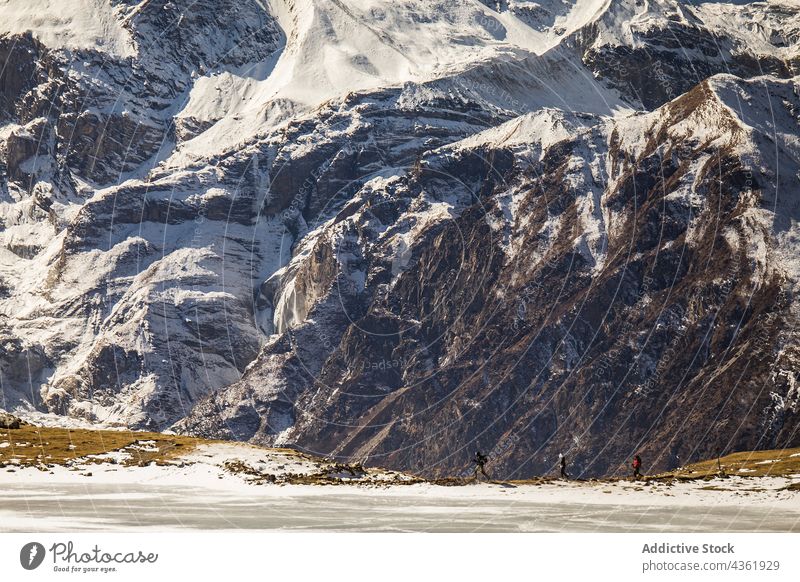 Unrecognizable travelers walking along mountainous valley in winter company hike snow group highland trekking himalayas nepal adventure together gather explore