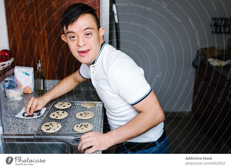 Happy ethnic boy with Down syndrome preparing cookies in kitchen down syndrome chocolate chip prepare bakery raw latin teen sweet table fresh food handicap