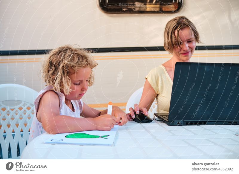 daughter drawing while mother works while in holidays in a camping caravan summer business woman family people laptop young boy internet office busy campsite