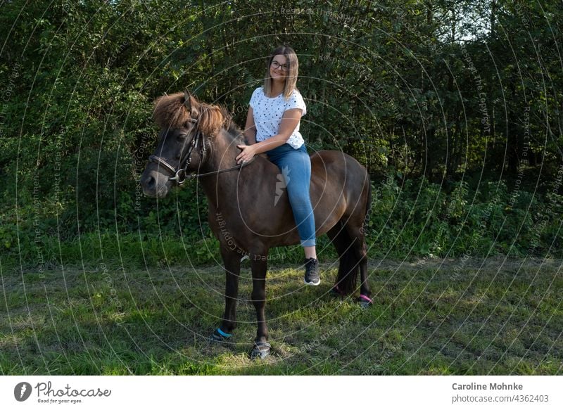 Young woman sitting contentedly on an Icelandic horse Woman Human being Adults Exterior shot Horse Icelander Bangs Brunette 18 - 30 years Colour photo