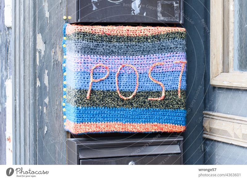 Close-up of a letterbox with the inscription POST colourfully knitted with coloured yarn on a half-timbered house Mailbox colored variegated embroidered
