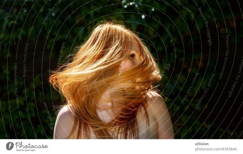 Sensual sexy portrait of beautiful redheaded woman shakes her hair outdoors with ivy background, copy space long stylish wavy sensual energy feminine freedom