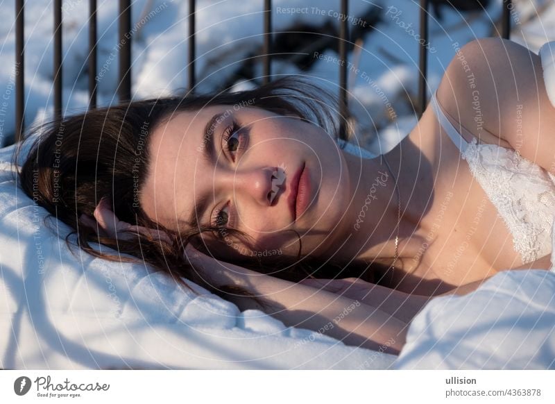 Portrait of an attractive, young, sexy, seductive woman in Bed, in white nightwear, head on hand Woman bed sleeping morning sun View dark brown pretty brunette