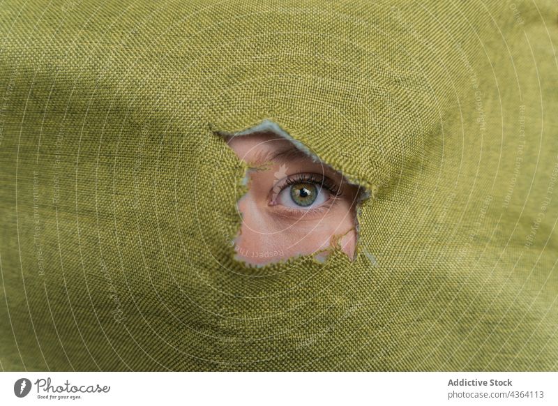 Woman with green eyes looking through hole in fabric woman color gaze stare hide cloth mystery beauty cover face female young feminine peep behind eyelashes