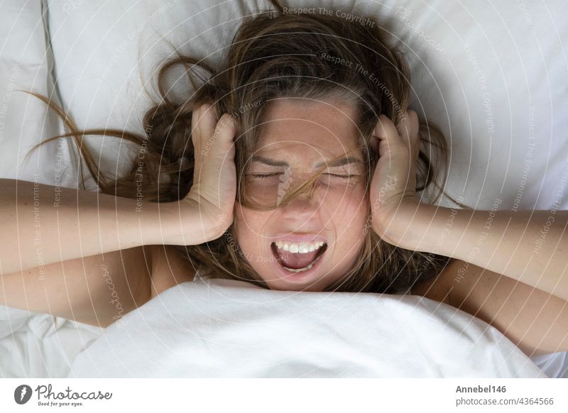 Young depressed unhappy woman lying in bed with health problems, screaming,hangover,depression,sleepless woman,migraine top view with white sheets insomnia