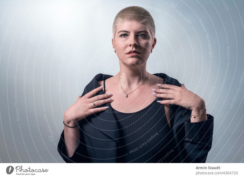 studio shot of a young, strong, beautiful woman with very short blond hair serious upright honest candid confident power powerful business piercing jewelry