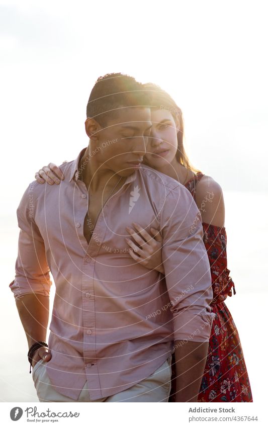 Tender multiethnic couple embracing on beach embrace love from behind seashore tender serene hug relationship multiracial diverse black african american