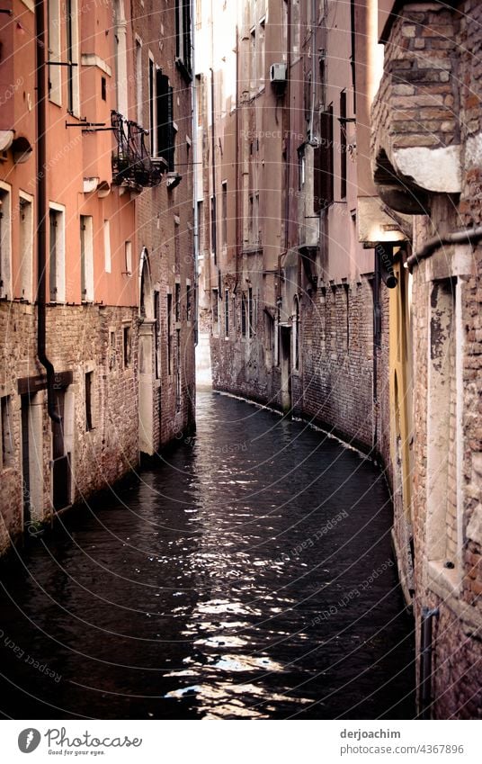 In a waterway of Venice. Old houses, not plastered, standing very close together. The water shimmers.  The sunlight penetrates the whole thing a little. The old shine of the houses has been lost for a long time.