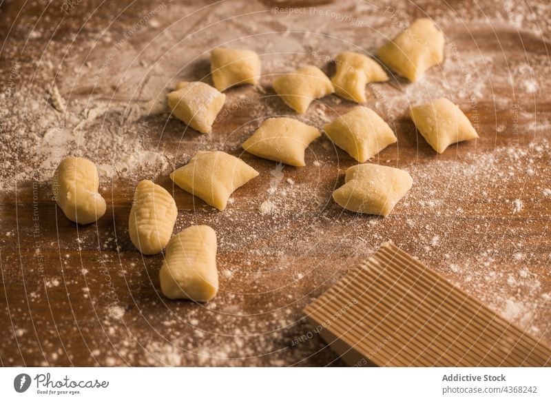 Raw pieces of dough near ribbed board gnocchi raw cook table flour ingredient kitchen prepare food fresh pasta italian authentic tradition meal homemade soft