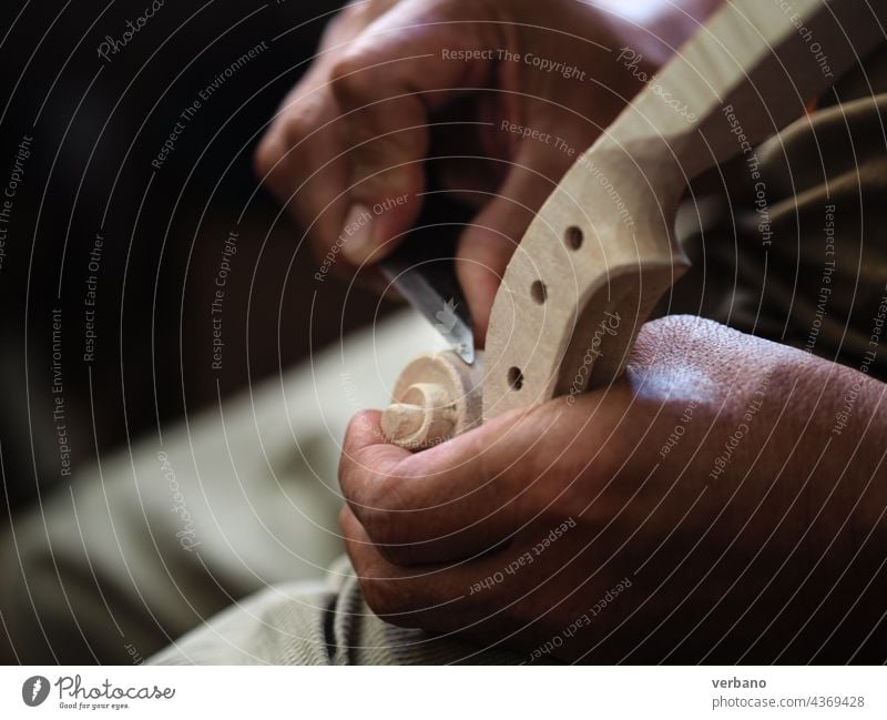 Violin maker artisan senior hands usign a knife to carve a Stradivarius model violin head and scroll luthier viola violinmaking carving wood sculpting cremona