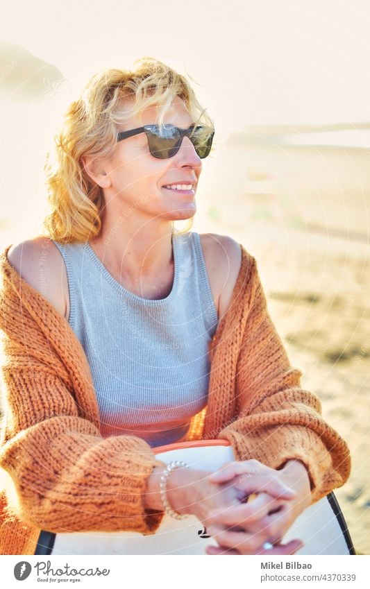 Portrait of a young mature blonde caucasian woman outdoor in a beach with a bodyboard and sunglasses in a sunny day. lifestyle portrait wellness women healthy