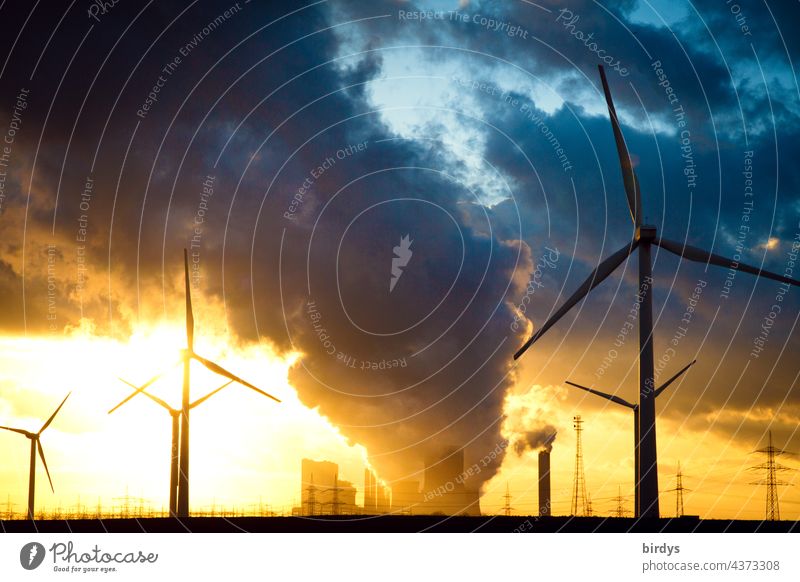 Wind turbines in front of a lignite-fired power plant at sunset in the backlight. Wind turbines Lignite power plant CO2 emission Climate change Air pollution