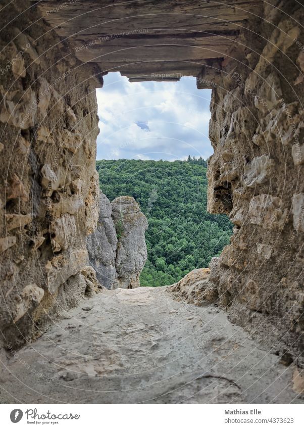 The view through an embrasure with rocks with forest in the background Summer Sand Sky Stone Exterior shot Colour photo Castle ruin Old times