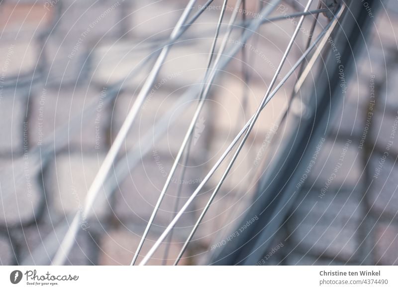 View through the spokes of a bicycle on beautiful cobblestones. Close up with a lot of blur Bicycle bicycle spokes Spokes Front wheel from on high Cobblestones