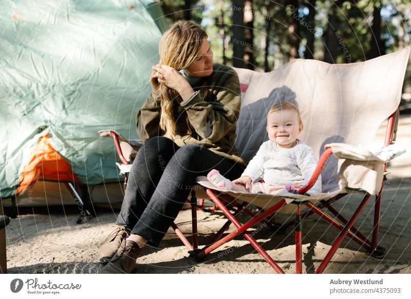 mother and her baby girl sitting on a camp chair outdoors while camping blonde california camp stove camper campsite caucasian child childhood cooking daughter