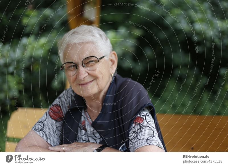 Senior woman sits at the edge of the forest and smiles 60 years and older portrait Female senior Woman Grandmother White-haired Gray-haired naturally Authentic