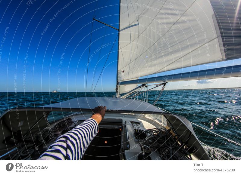 one hand holds on to the ship Sailor Seaman Hand arm Striped sweater Human being Sailing ship Watercraft Sailboat Navigation Sky Ocean Yacht Vacation & Travel