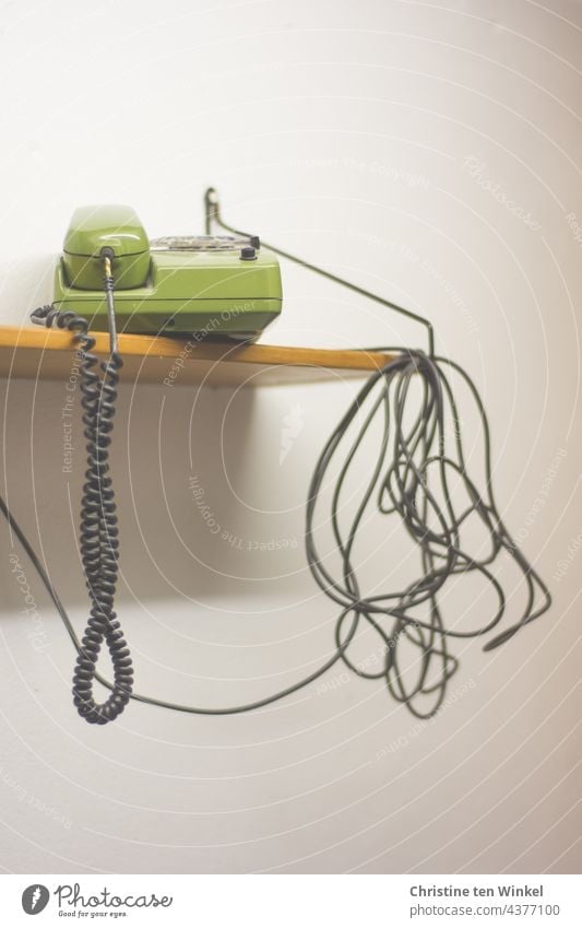 Here we have the salad | cable tangle and a green telephone on a wooden shelf in front of a white wall Cable Telephone cable dial telephone green phone Retro