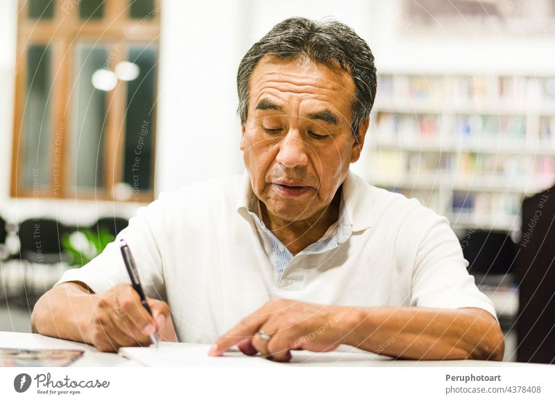 Serious senior man sitting on a library bench writing in his book. classroom education learning notes knowledge lifestyle people person research study studying