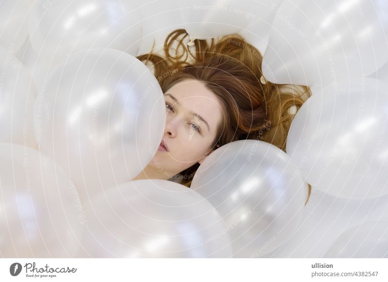 View from above beautiful young woman face between white iridescent balloons, beauty fashion concept. vogue redhead romantic bridal wedding love looking closeup