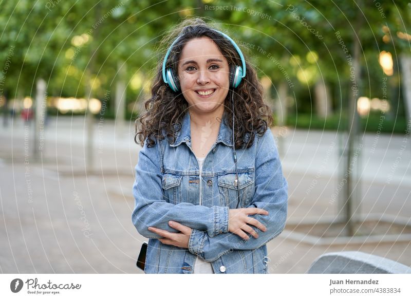 woman listens to music with her headphones connected to her smartphone young smart phone mobile phone cellular cellphone cell phone headset earphones listening