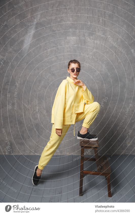 Young woman in yellow sweatshirt and sunglasses on a gray background portrait model young female fashion yelow girl closeup studio hair face beauty sensual