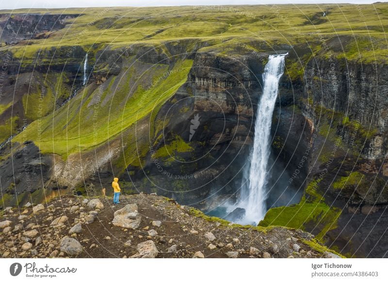 Aerial view of man standing on the cliff edge enjoying Iceland highland valley and Haifoss waterfall aerial landscape river above iceland haifoss stream green