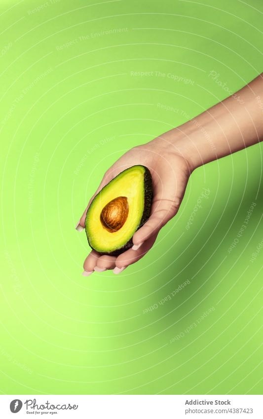Crop woman showing fresh avocado half with seed fruit vitamin healthy food tropical natural exotic soft cut pulp delicious unpeeled bright demonstrate oval hand