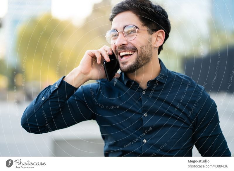 Young man talking on the phone outdoors. young mobile urban smiling smile connection gadget portrait positive wireless telephone holding walking looking typing