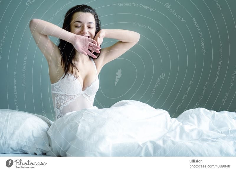 Portrait of an attractive, sexy dark brown haired woman sitting in Bed, Copy space. bed young caucasian happy beautiful female pretty relax girl bedroom home