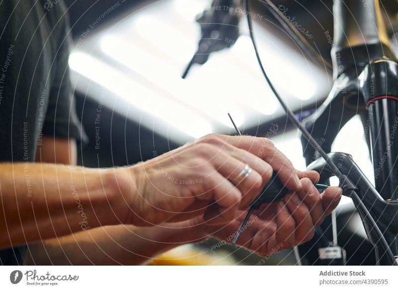 Mechanic fixing brake cable of bicycle in garage mechanic man workshop bike repair service male equipment professional job metal occupation worker guy manual