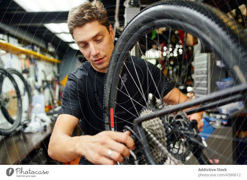 Man fixing bicycle wheel in garage man technician repair attach professional work service male adult cycling mechanic workshop maintenance repairman transport