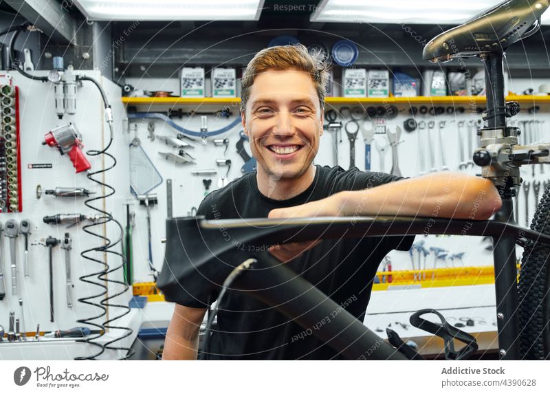 Cheerful man in bicycle repair workshop mechanic professional smile lean industry male adult small business garage cycling transport happy service fix bike