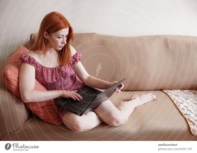 woman using laptop computer at home relaxing on sofa real people authentic living room couch work home office freelance young adult person mobility reading