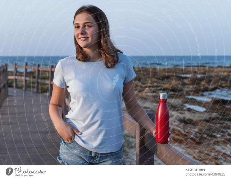 Blue haired Teenage girl in blue hoodie staying near graffiti wall with red water  bottle Stock Photo by katrinshine