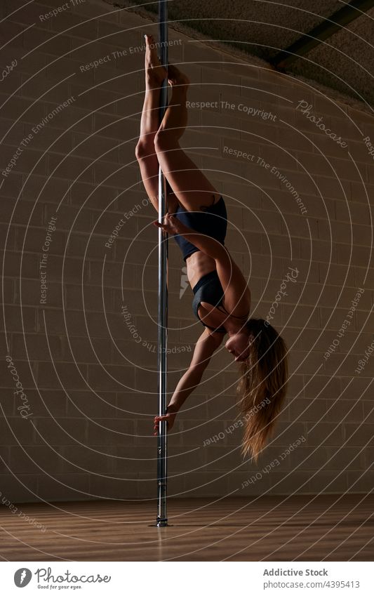 Female pole dancer performing handstand in studio woman flexible rehearsal grace gymnastic female pylon acrobatic upside down practice stretch professional slim