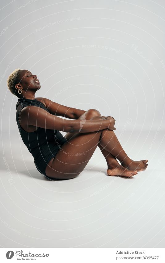 alluring african american woman in sexy tights and bodysuit posing next to  black cube, fashion Stock Photo by LightFieldStudios