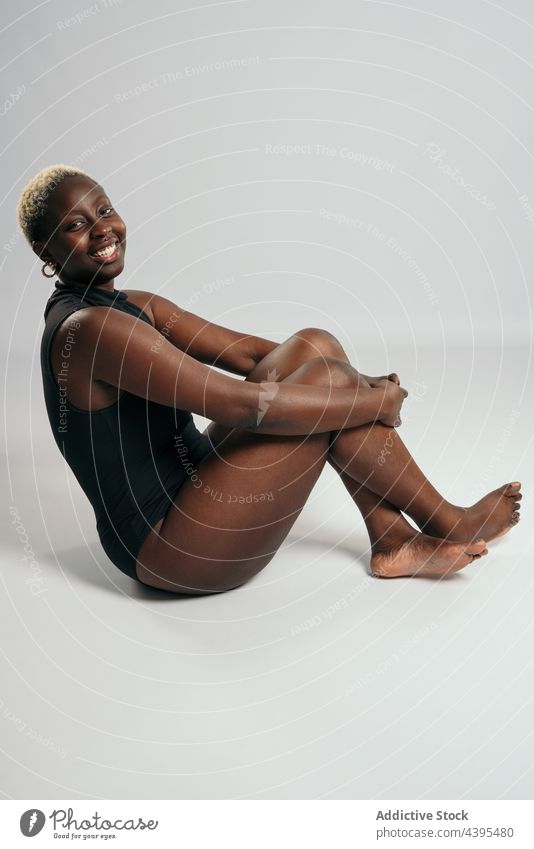 Fotografia do Stock: Curvy beautiful African American woman with braids in  lingerie keeping hands on waist and looking at camera against yellow  background