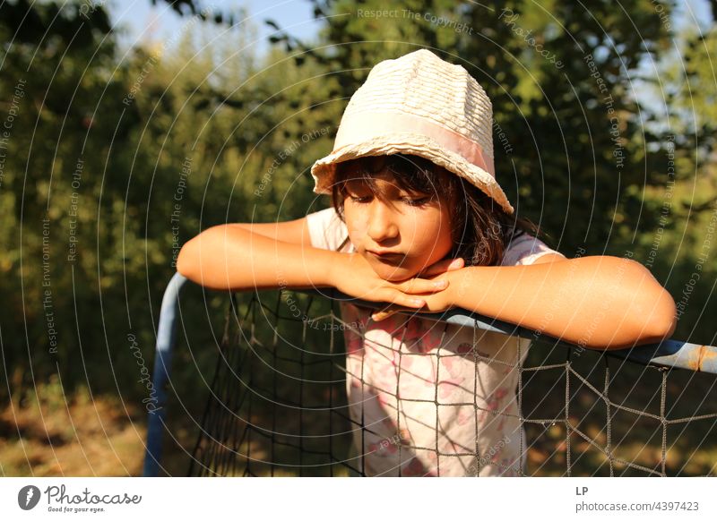 child alone wearing a hat and leaning on a pole looking down and appearing to be sad Risk Longing Individual Isolated Single Abstract Flow Children's game
