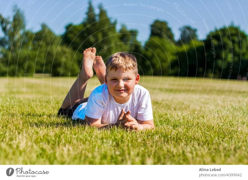 A cheerful child smiles with joy. I am happy to walk and play on the lawn in warm sunny weather in the park. the emotions of children on the face. boy happiness