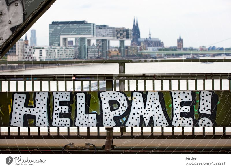 Help me. Graffiti on a railway bridge in Cologne, in the background, the Rhine, the Cologne Cathedral and the crane houses. Cry for help Needy Seeking help
