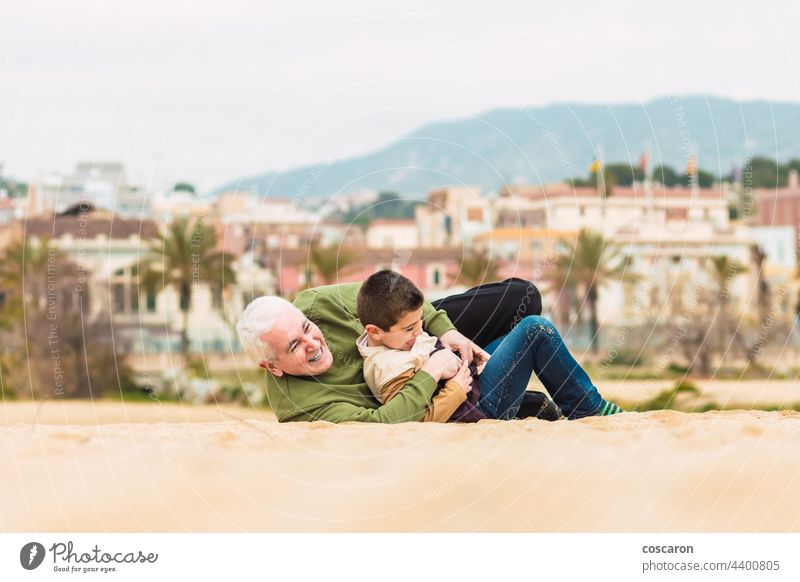 Funny boy and his grandfather playing stretched out in the sand on the beach active caucasian child childhood cute el masnou family fun generation generations