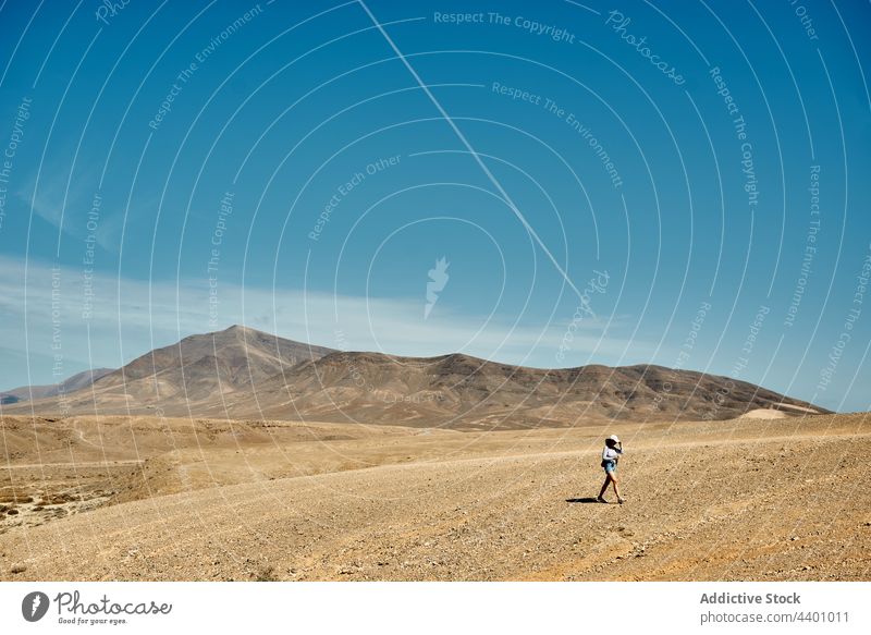 Woman walking in desert near mountains woman traveler dry valley blue sky summer nature fuerteventura spain canary islands trip landscape tourism journey range