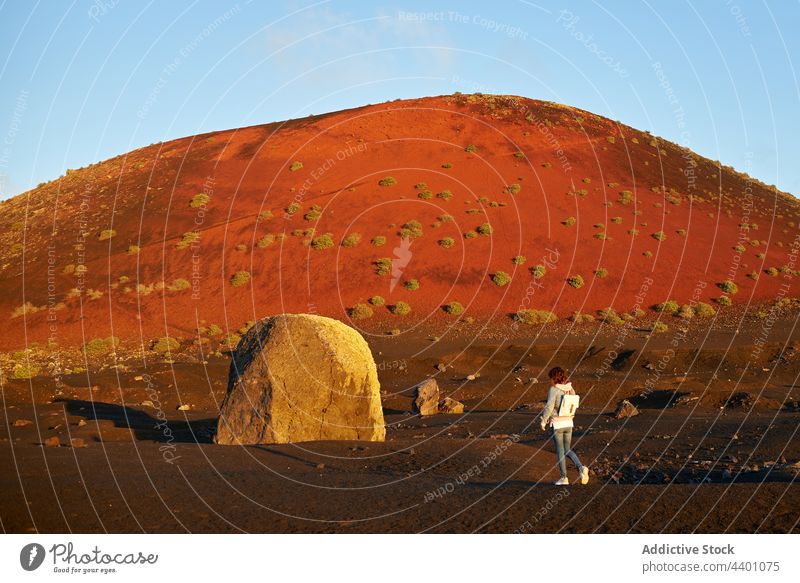 Woman walking near hill and stone woman countryside dry summer traveler explore daytime fuerteventura spain canary islands nature female tourism journey trip