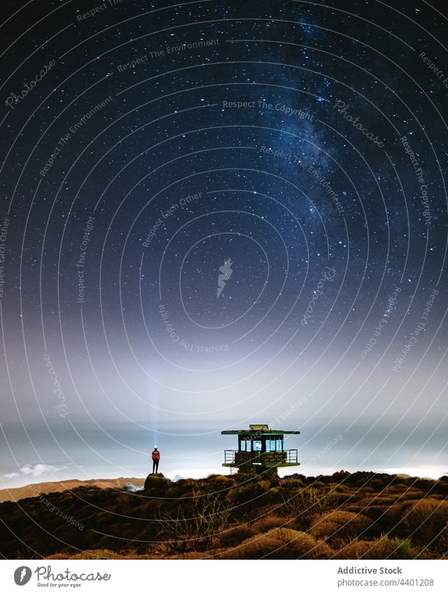 Person on beach under starry sky with Milky Way at night person milky way glow rescue tower nature dark universe luminous glimmer constellation landscape scenic