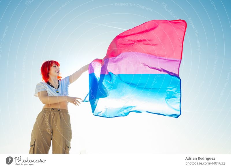 Woman holding the Bisexual Rainbow Flag with the blue sky in the background flag lgbt homosexual bisexual pride lesbian rights lgbtq rainbow love homosexuality