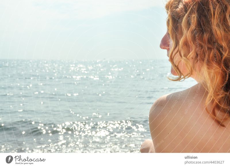 Beautiful portrait in profile closeup of a young red-haired curly woman by the sea on the beach in Italy with copy space, space for text red hair italy girl