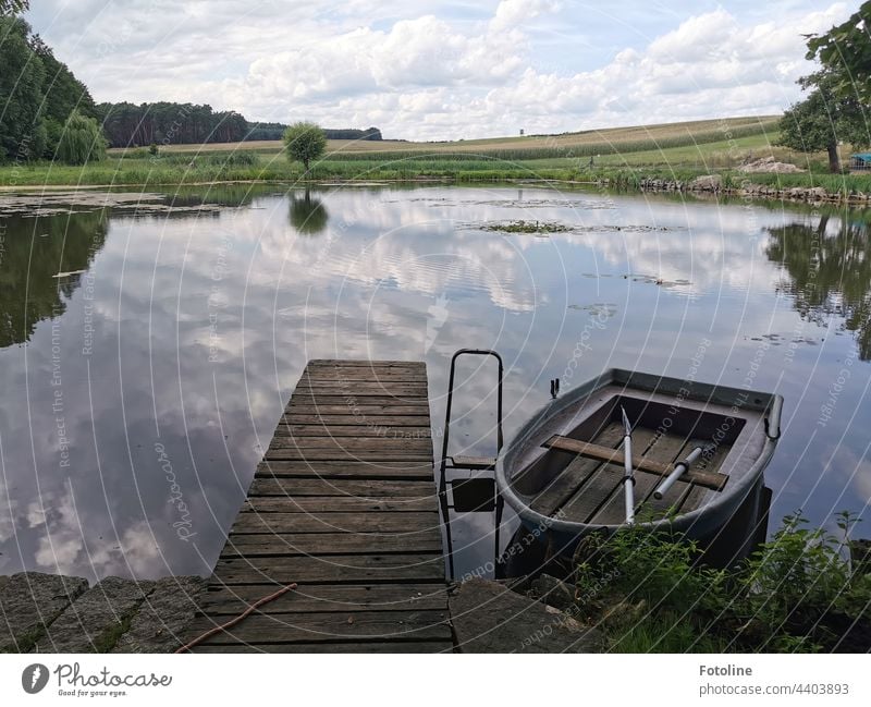 old wooden fishing boat reflected on water at a small lake pond