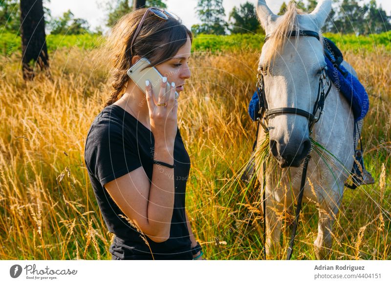 Female vet being on the phone while standing by horse in the countryside technology together holding woman animal female happy equestrian center care