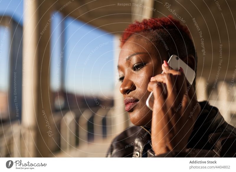 Afro woman talking on her smartphone black afro serious holding app girl trendy lifestyle adult background using ethnic urban cell portrait person young stylish